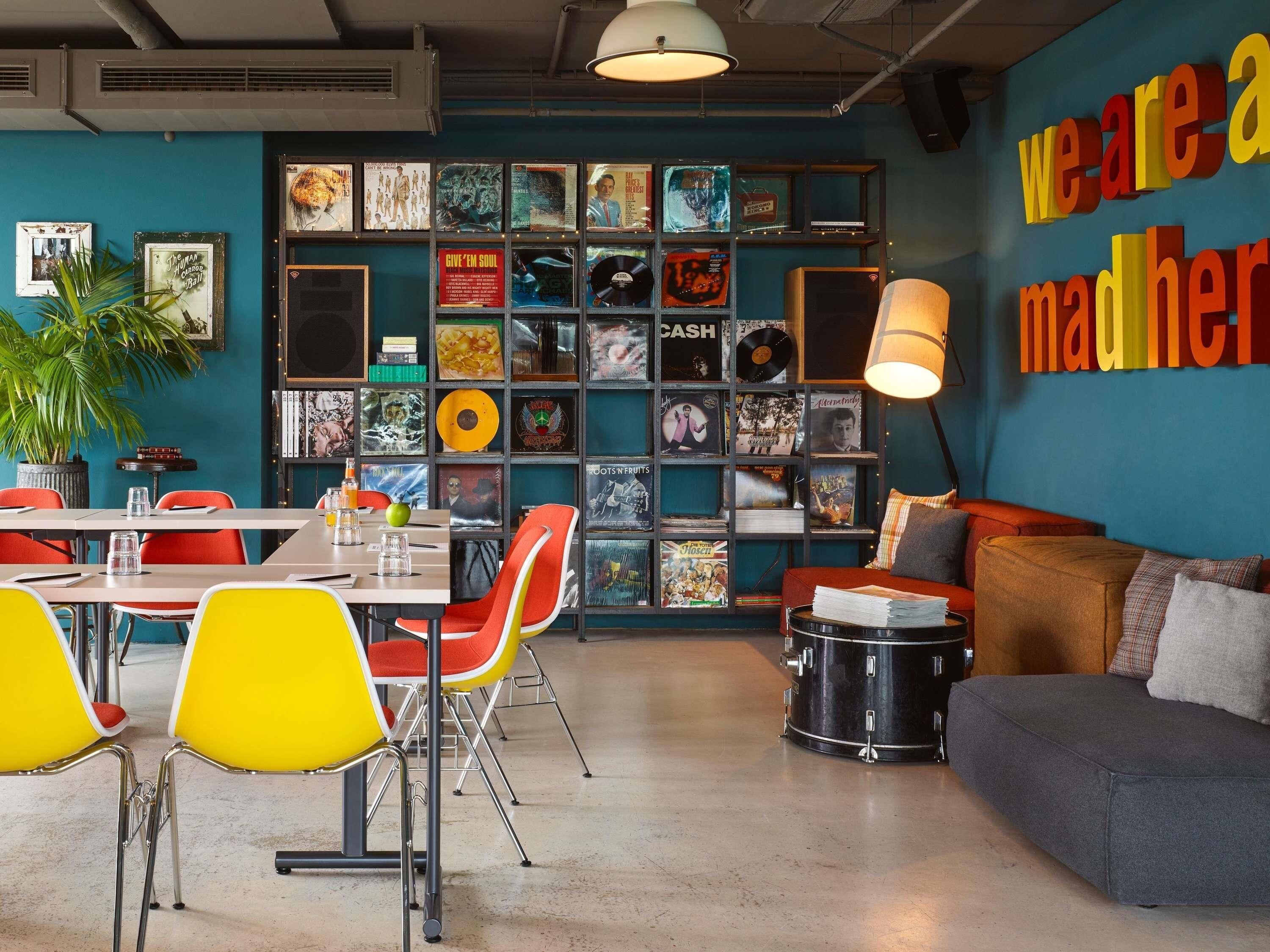 A room with a blue wall, a bookshelf filled with vinyl records, a drum set, and a couch.