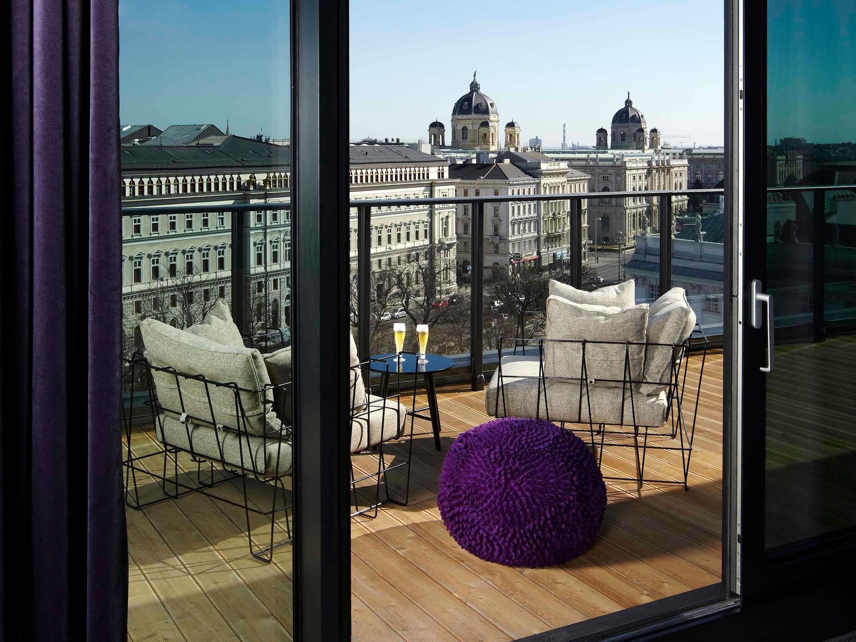 A balcony with seating, a table, and a purple ottoman.