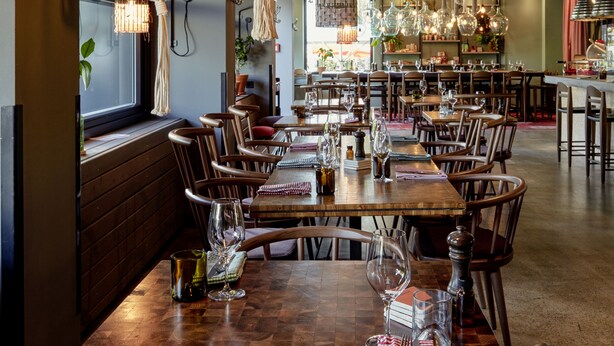 A restaurant interior with wooden tables, hanging macramé planters, and pendant lighting. - 25hours Hotel Vienna at MuseumsQuartier (Vienna)