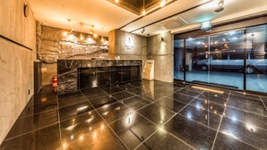 A modern hotel lobby with a marble reception desk, a stone wall feature, and a glass entrance. - Hotel Seattle Incheon Airport (Incheon)