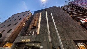 A hotel with a prominent 'HOTEL SEATTLE' sign, a modern architectural design with a geometric facade, and a visible entrance with a glass door. - Hotel Seattle Incheon Airport (Incheon)