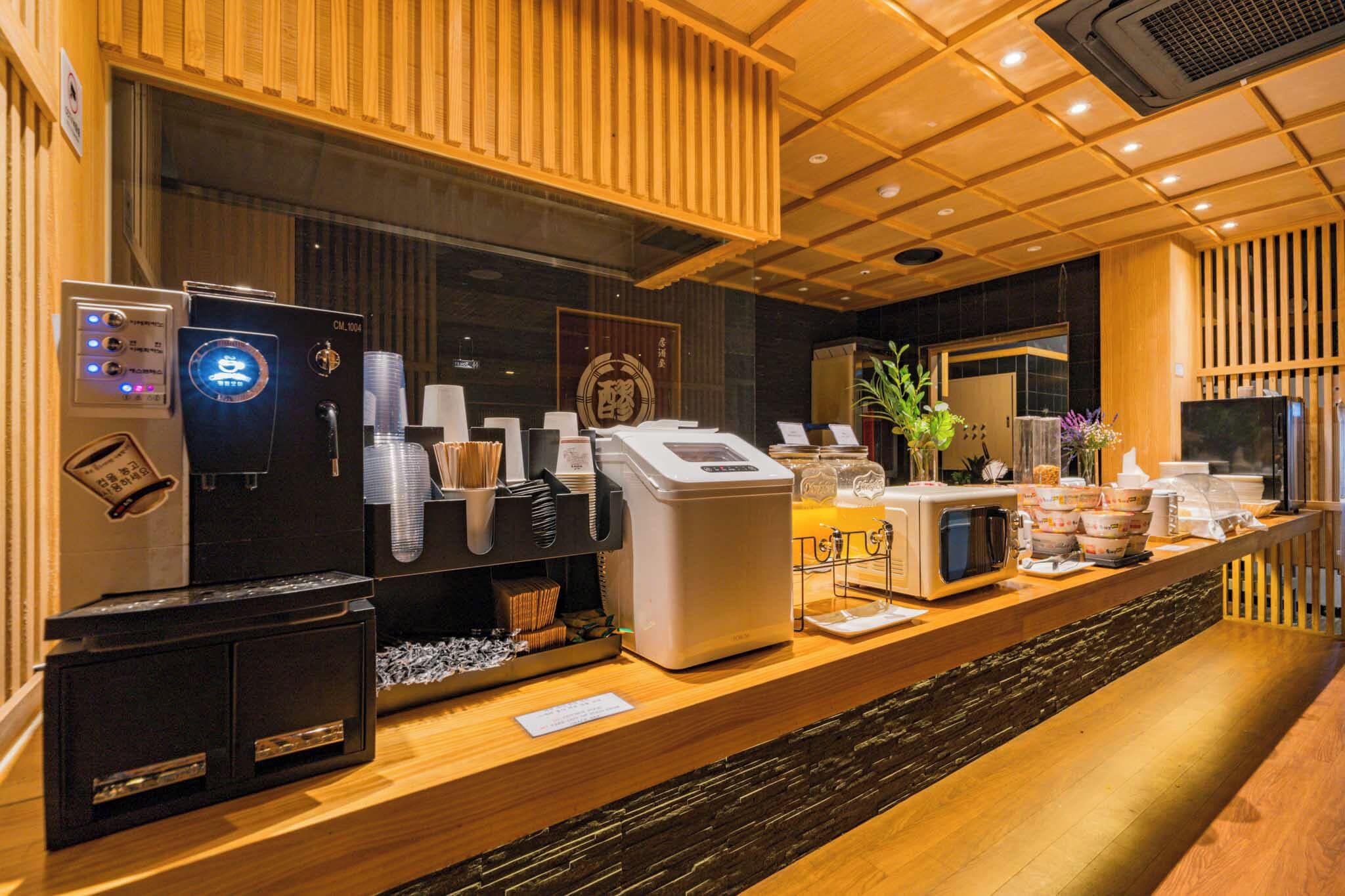 Una estación de café con cafetera, dispensador de té y microondas.