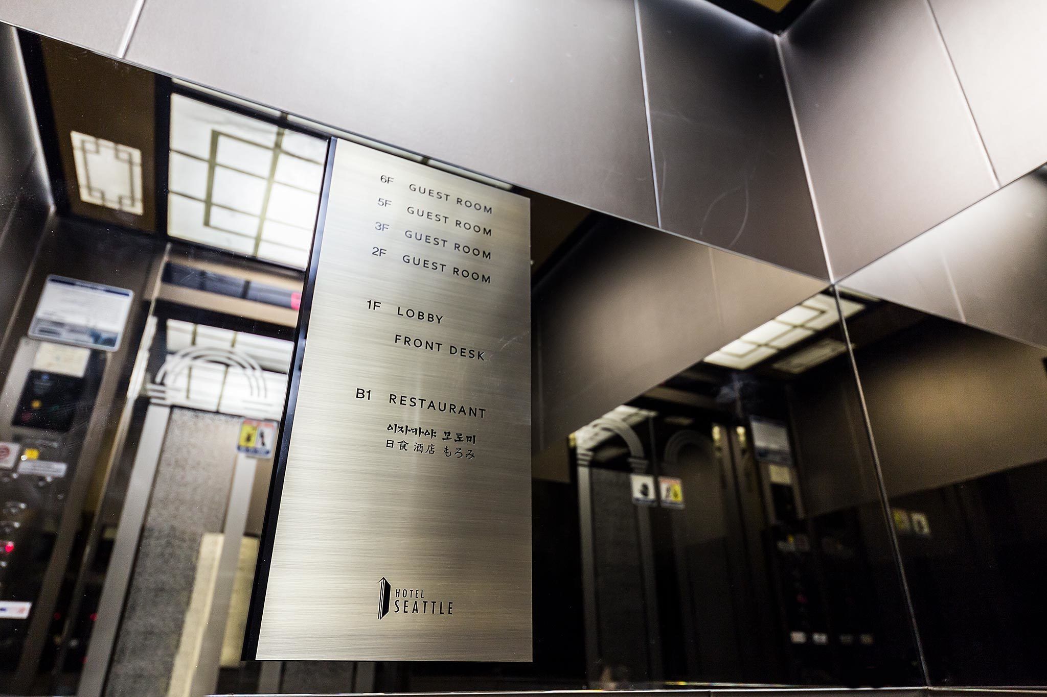 A hotel elevator interior with a sign listing floors and their purposes, including guest rooms, a lobby, a front desk, and a restaurant.