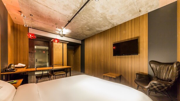 A hotel room with a large bed, a desk with a chair, a television mounted on the wall, and a leather chair. - Hotel Seattle Incheon Airport (Incheon)