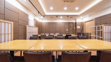 A conference room with a long table, chairs, and a small kitchenette.