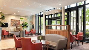 Eine moderne Hotelhalle mit Sitzgelegenheiten, großen Fenstern und einer Rezeption.