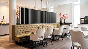 A modern dining area with a central bench, multiple chairs, and a long table.