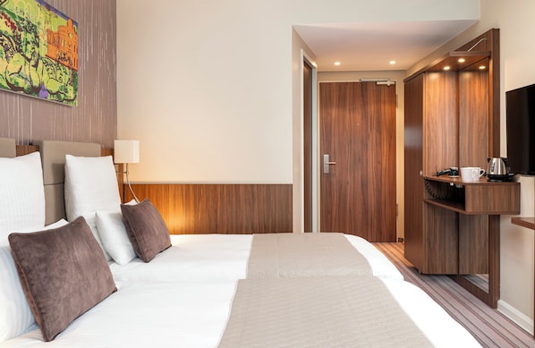 Habitación de hotel con una cama grande, televisión, armario y un cuadro en la pared.