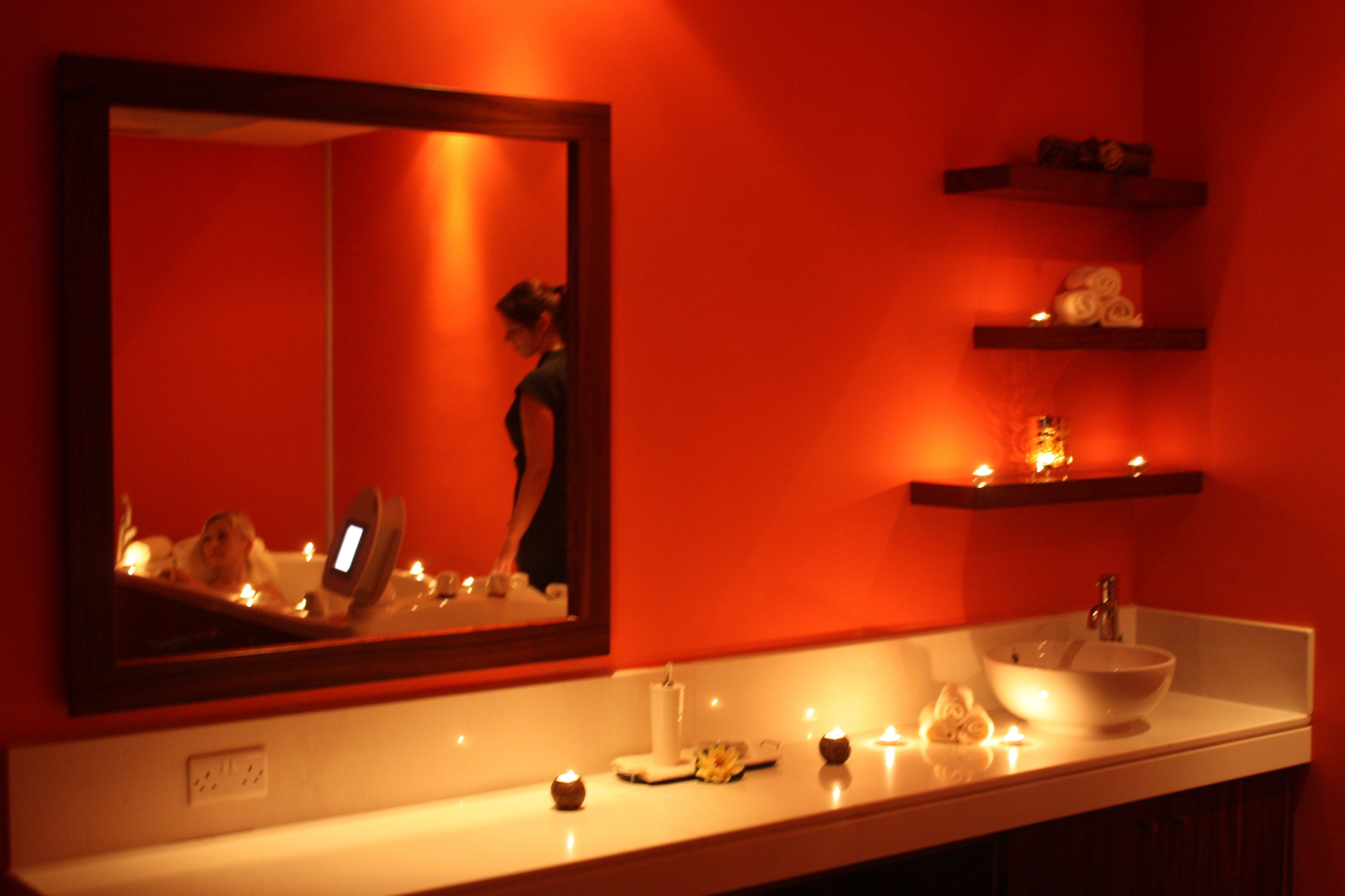 A bathroom with a large mirror, a sink, and shelves with toiletries.