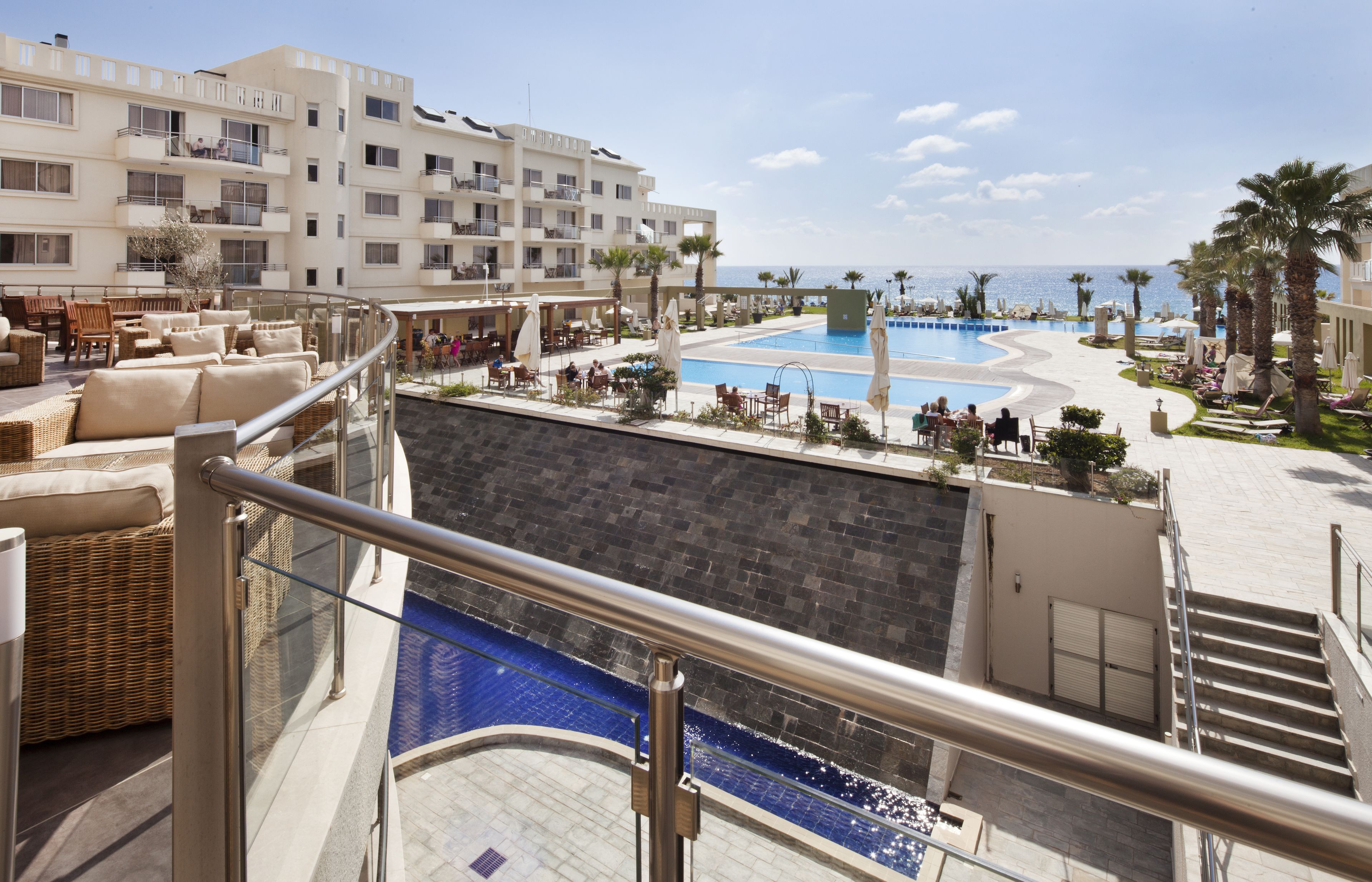 Un hotel amb zona de piscina, seients exteriors i vistes al mar.