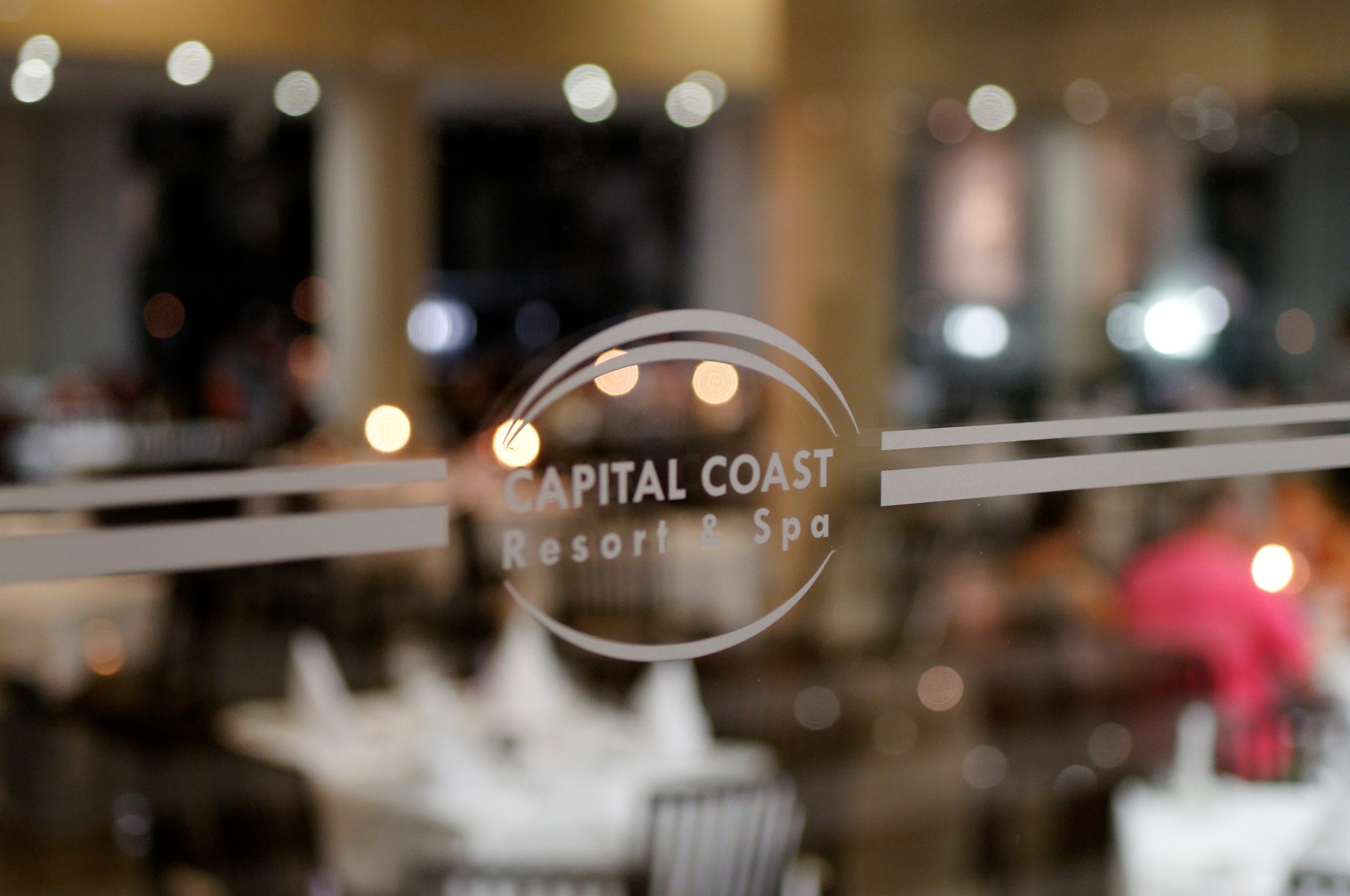 Interior borroso de un hotel con un cartel que dice 'Capital Coast Resort & Spa'.