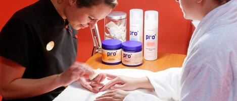 A nail care session with a professional and a client, featuring products labeled 'pro'.