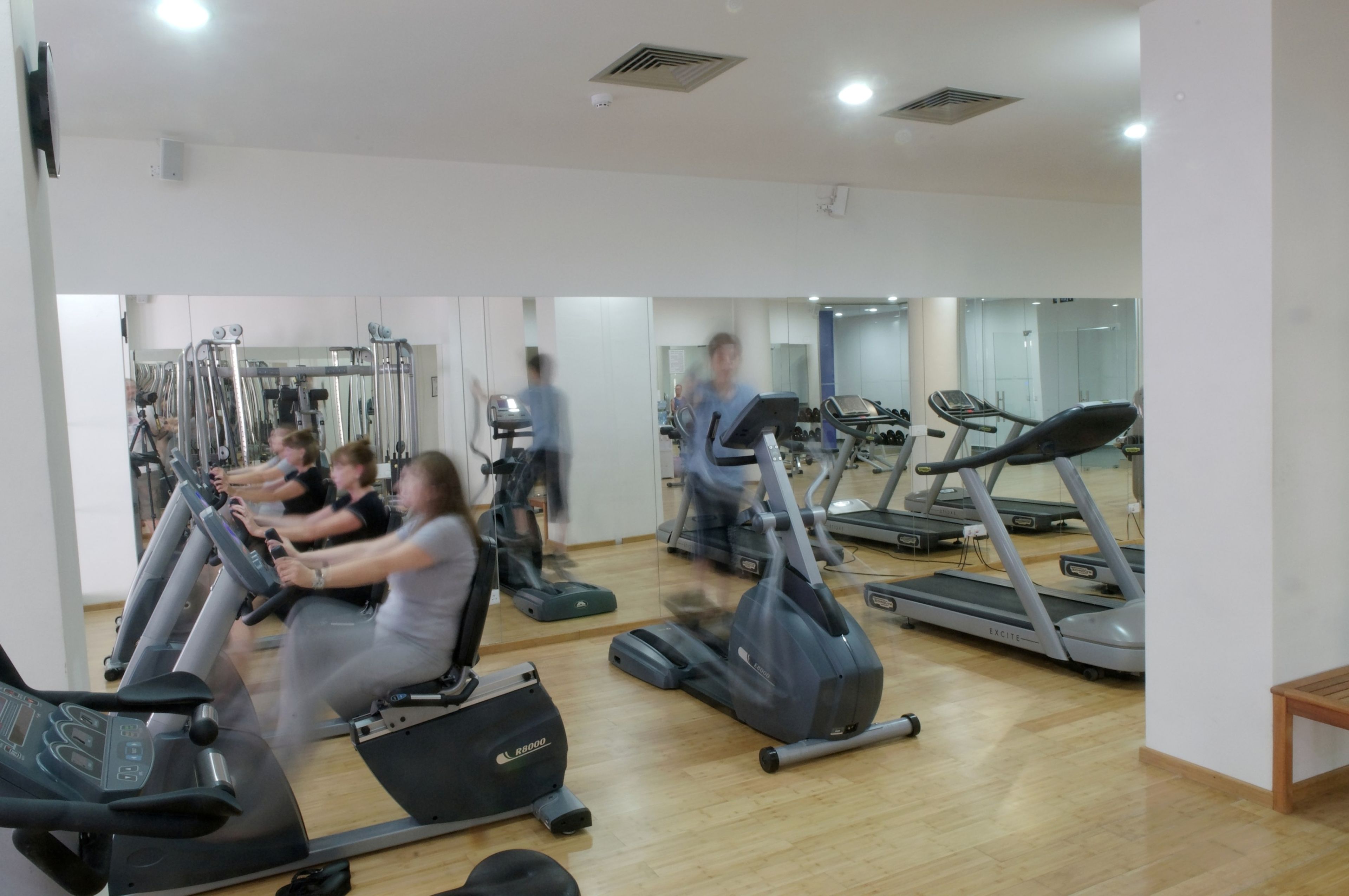 Un gimnasio con varias cintas de correr y equipo de ejercicio.