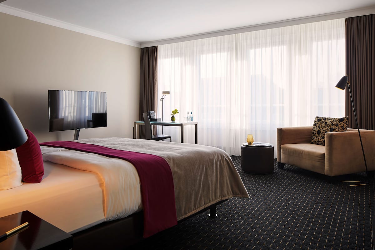 Una habitación de hotel con una cama, un escritorio, una silla, un televisor y una lámpara.
