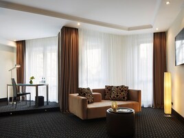 Ein Hotelzimmer mit Sofa, Couchtisch, Schreibtisch mit Stuhl und Lampe.