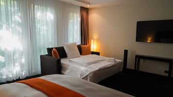 A hotel room with two beds, a TV, a lamp, and a window with curtains.