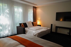 Habitación de hotel con dos camas, televisión, lámpara y ventana con cortinas.