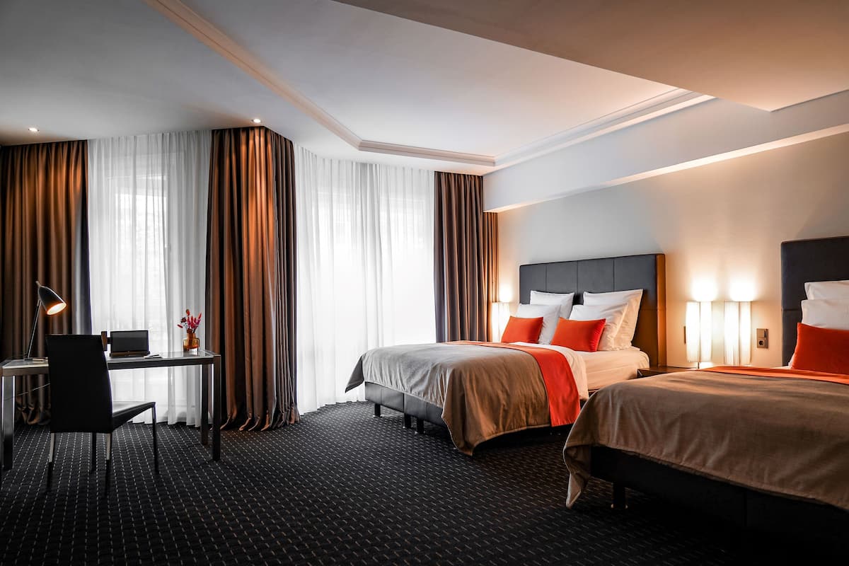 Habitación de hotel con dos camas, un escritorio y una silla.