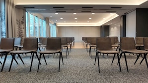 A conference room with rows of chairs, large windows, and a carpeted floor. - Erikson Hotel (Sindelfingen)
