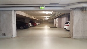 A parking garage with multiple levels, concrete walls, and a green emergency exit sign. - Erikson Hotel (Sindelfingen)