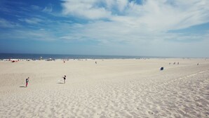 A wide sandy beach with footprints and a few people scattered across it. - Daddy O Hotel (Beach Haven)