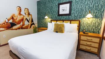 Habitación de hotel con una cama grande, dos mesitas de noche con lámparas, un cuadro enmarcado en la pared y una pared verde con textura.