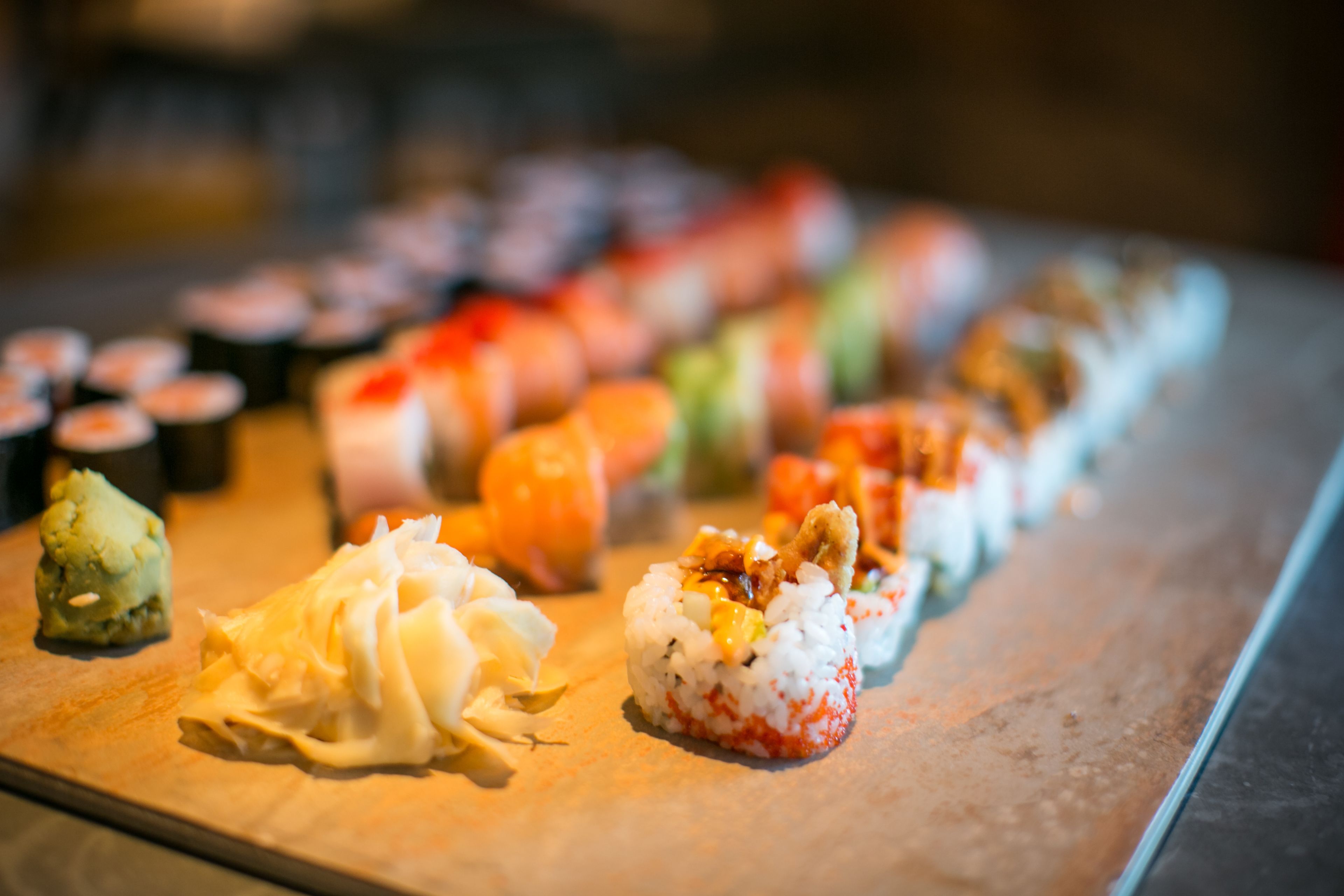 Ett fat med olika sorters sushi, upplagt på ett träbord.