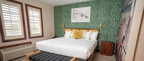 A bedroom with a bed, a bench, a heater, and a wall with a picture.