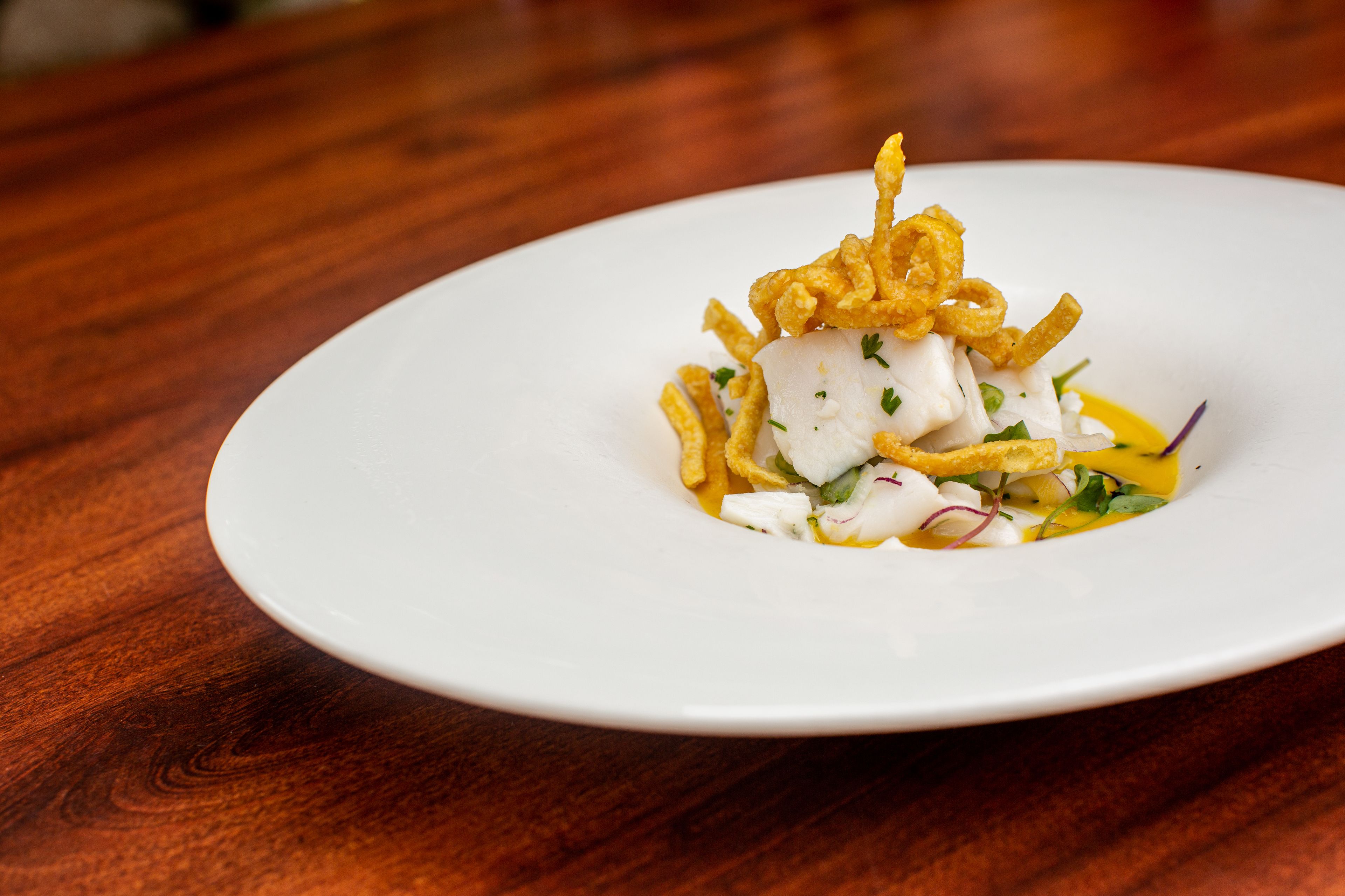 A white plate with a seafood dish on a wooden table.