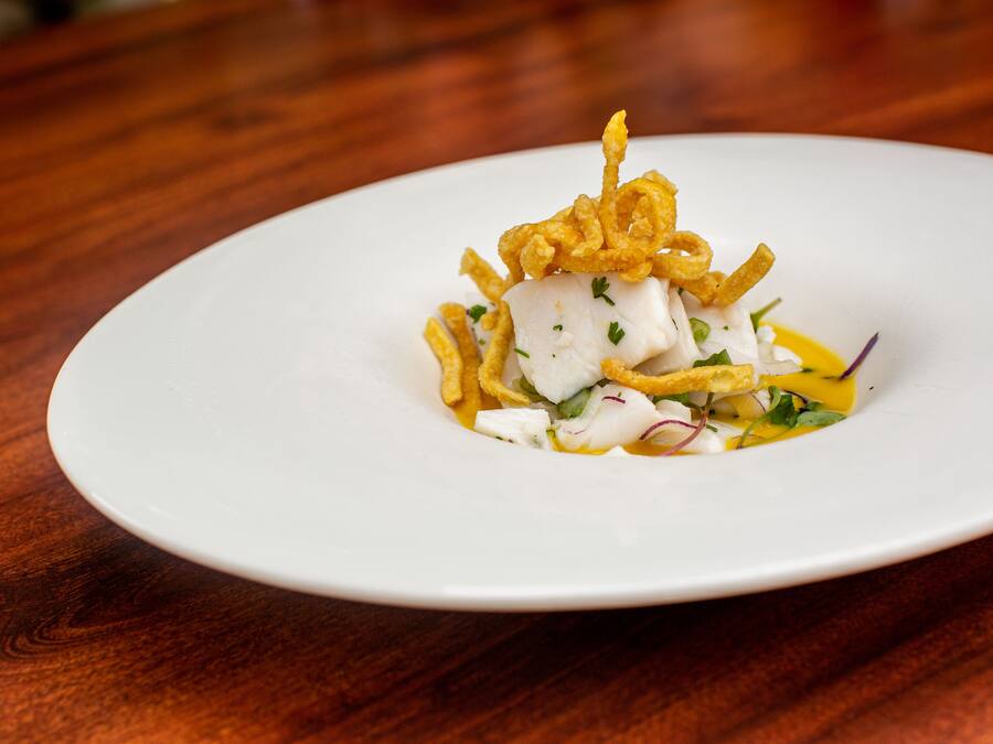 A white plate with a seafood dish on a wooden table.