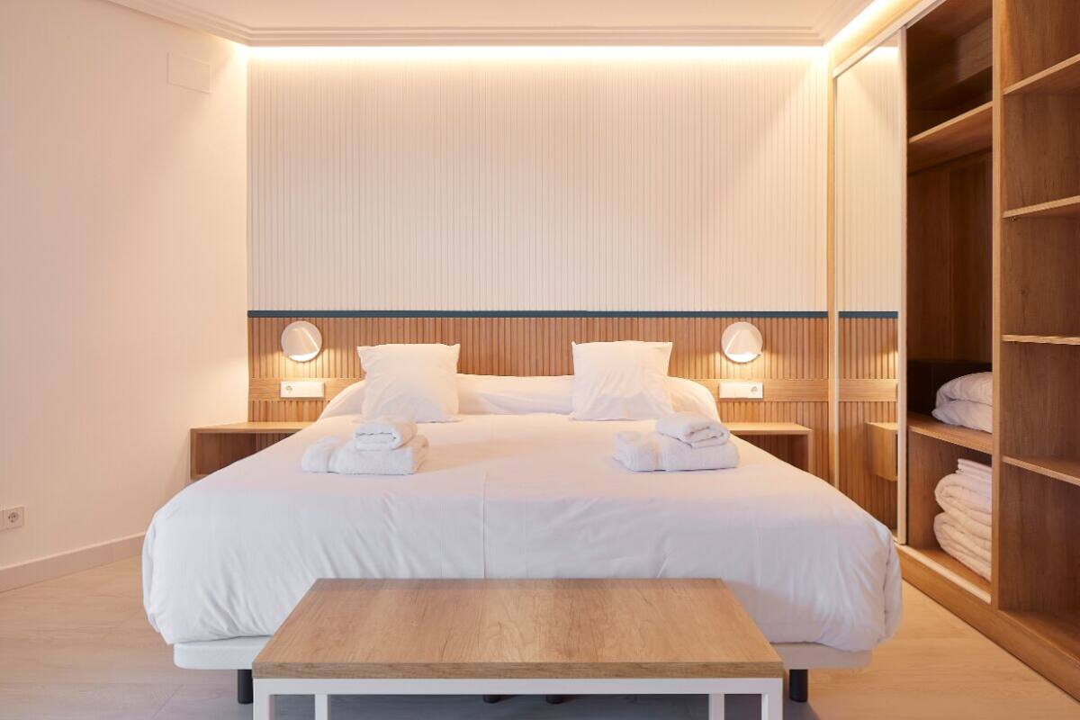 A neatly arranged hotel room with a large bed, bedside tables, and a wooden wardrobe.