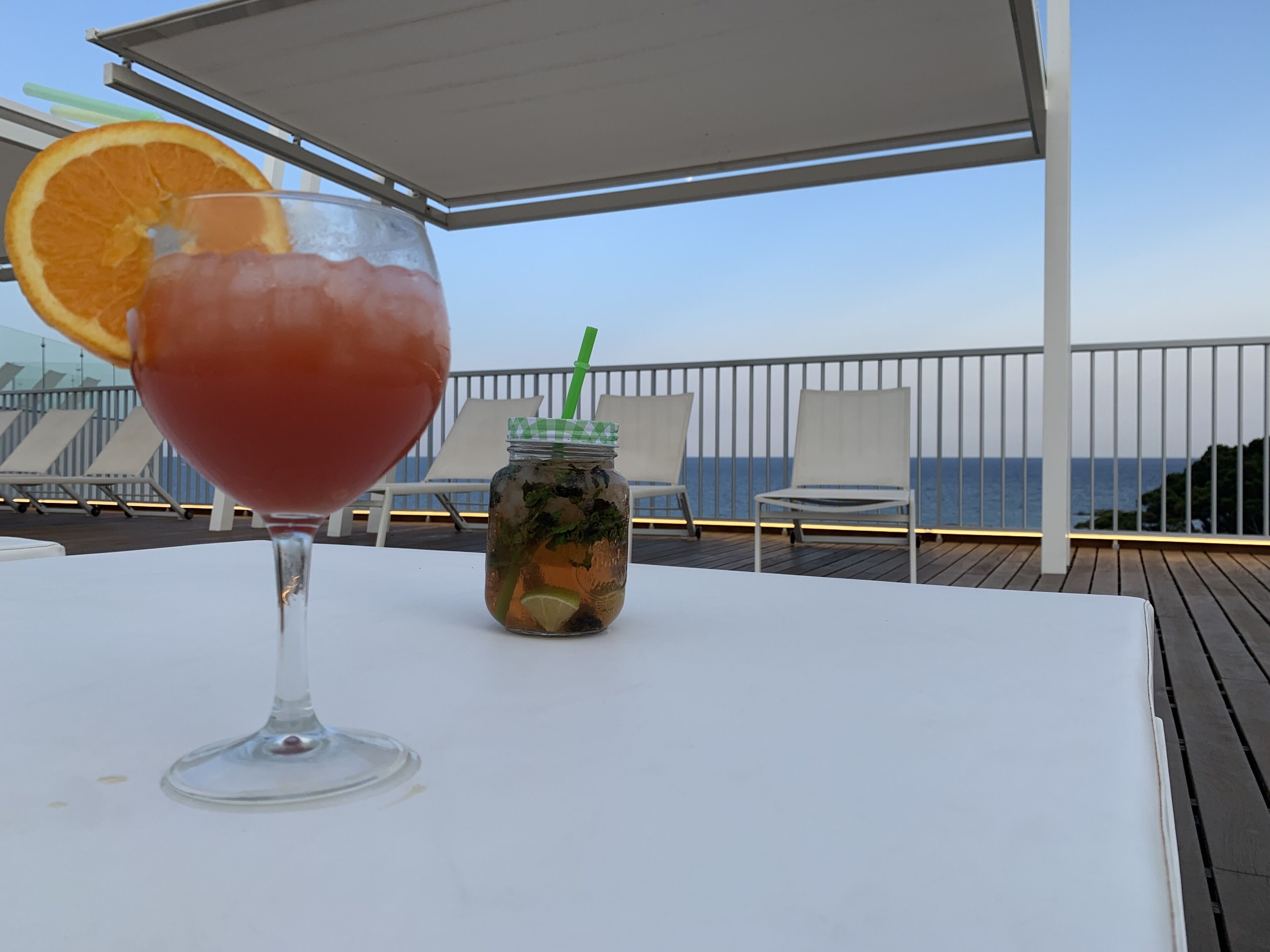 Ein Tisch mit einem Glas Eistee und einem Einmachglas mit einem grünen Strohhalm.