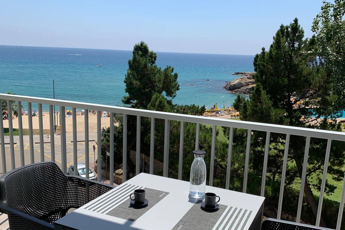 A balcony with a table and chairs overlooking a beach.