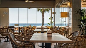 A restaurant with wicker furniture and a view of the sea.
