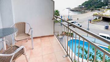 A balcony with a view of a beach and a pool.