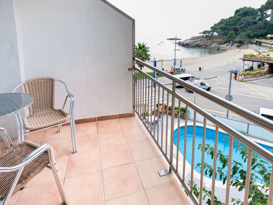 A balcony with a view of a beach and a pool.