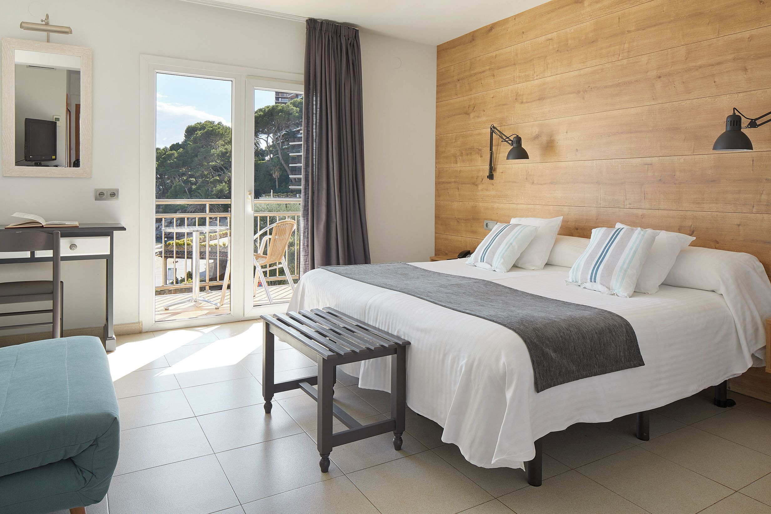 Une chambre à coucher comprenant un lit, une table de chevet, une chaise et donnant sur l’extérieur.