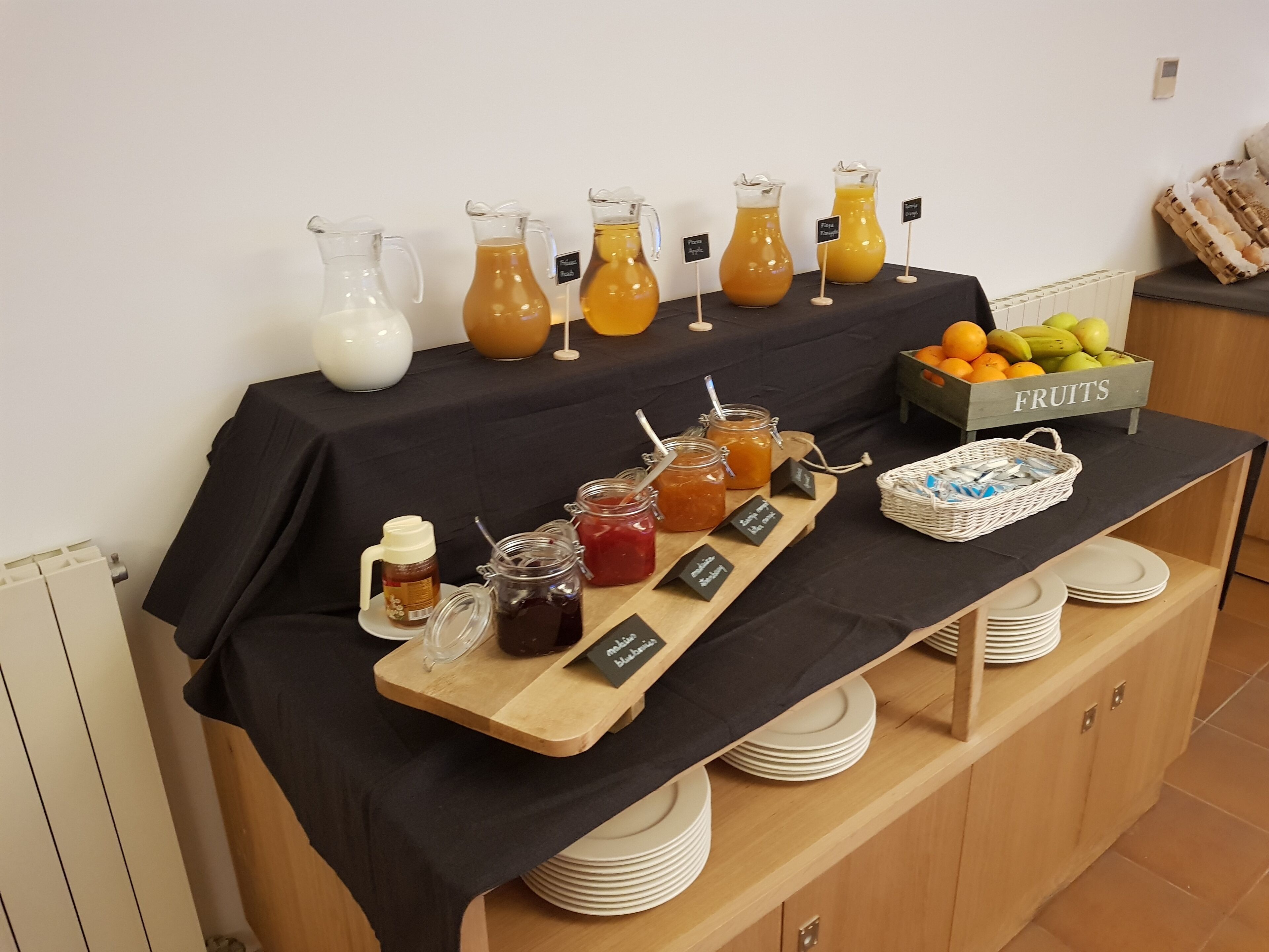Una mesa de buffet con diversas bebidas y una cesta de frutas.