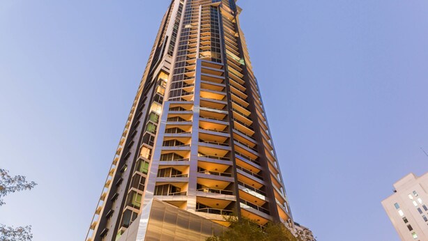 A tall, modern high-rise building with multiple balconies and a clear sky. - Mantra On Mary (Brisbane)