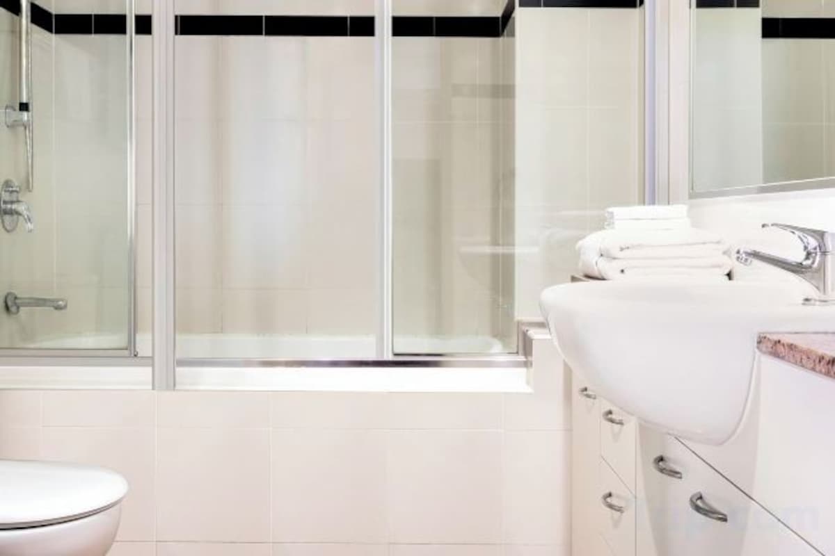 A bathroom with a glass shower enclosure, a white sink, and a toilet.