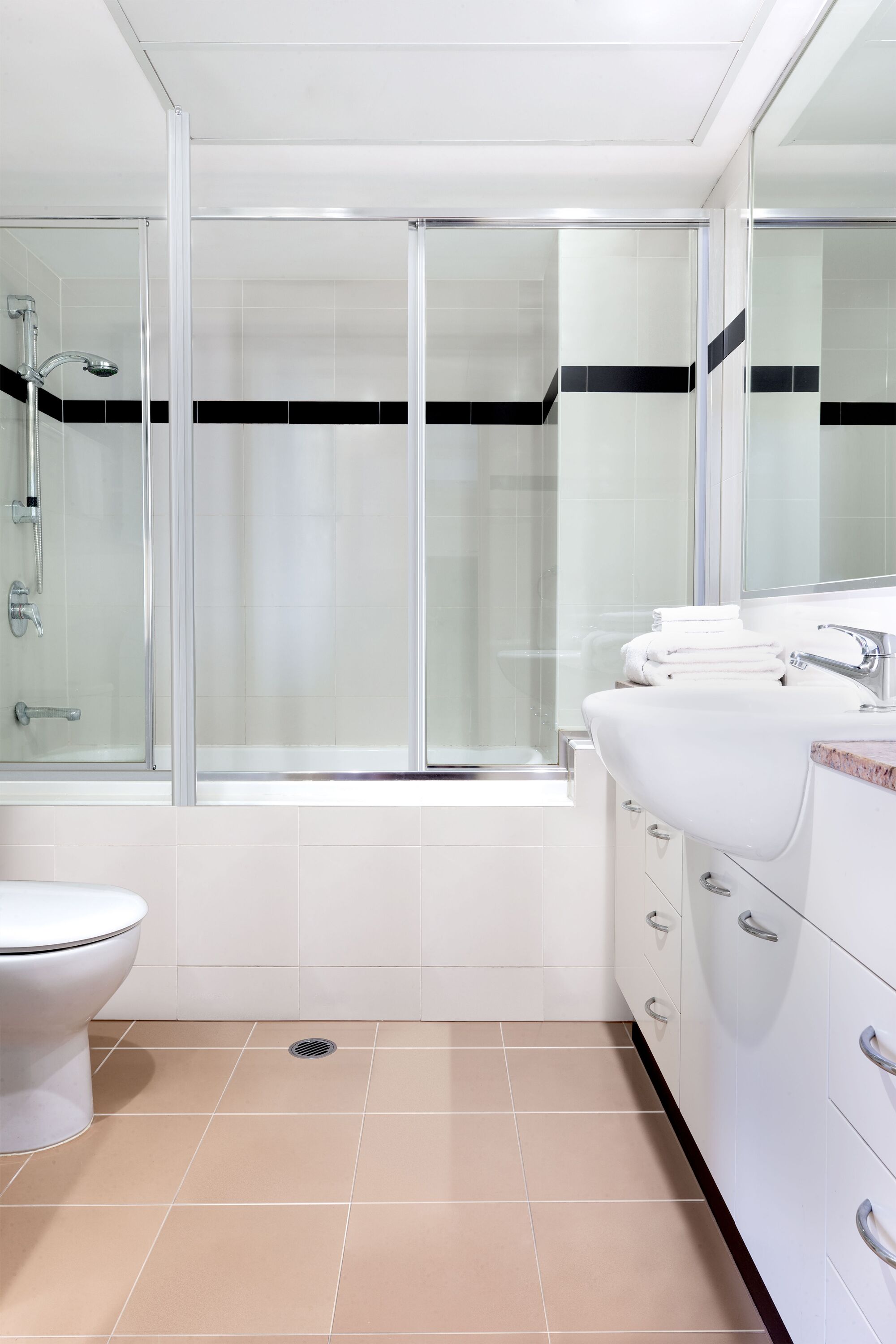 A modern bathroom with a glass-enclosed shower, a white sink, and a toilet.
