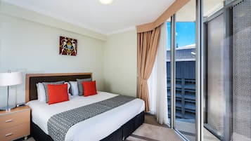 A hotel room with a large bed, a nightstand, a window with a view of the outside, and a ceiling light.