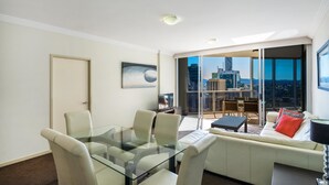 A modern hotel room with a glass dining table, a sofa, and a city view through large windows. - Mantra On Mary (Brisbane)