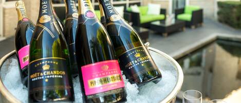 A bucket of champagne bottles on ice with glasses beside it.