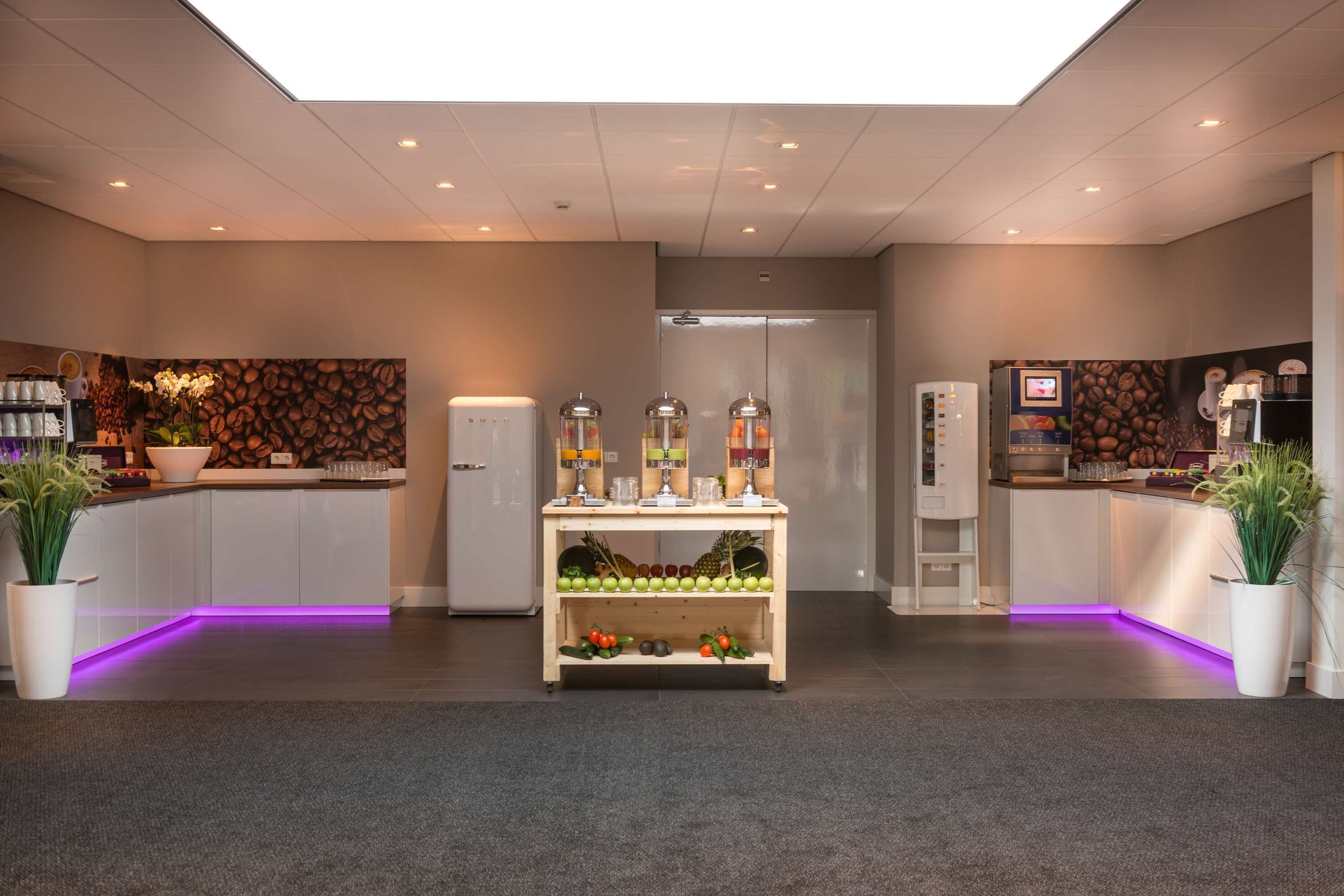 A modern kitchen with a central island, coffee machines, and a fruit display.