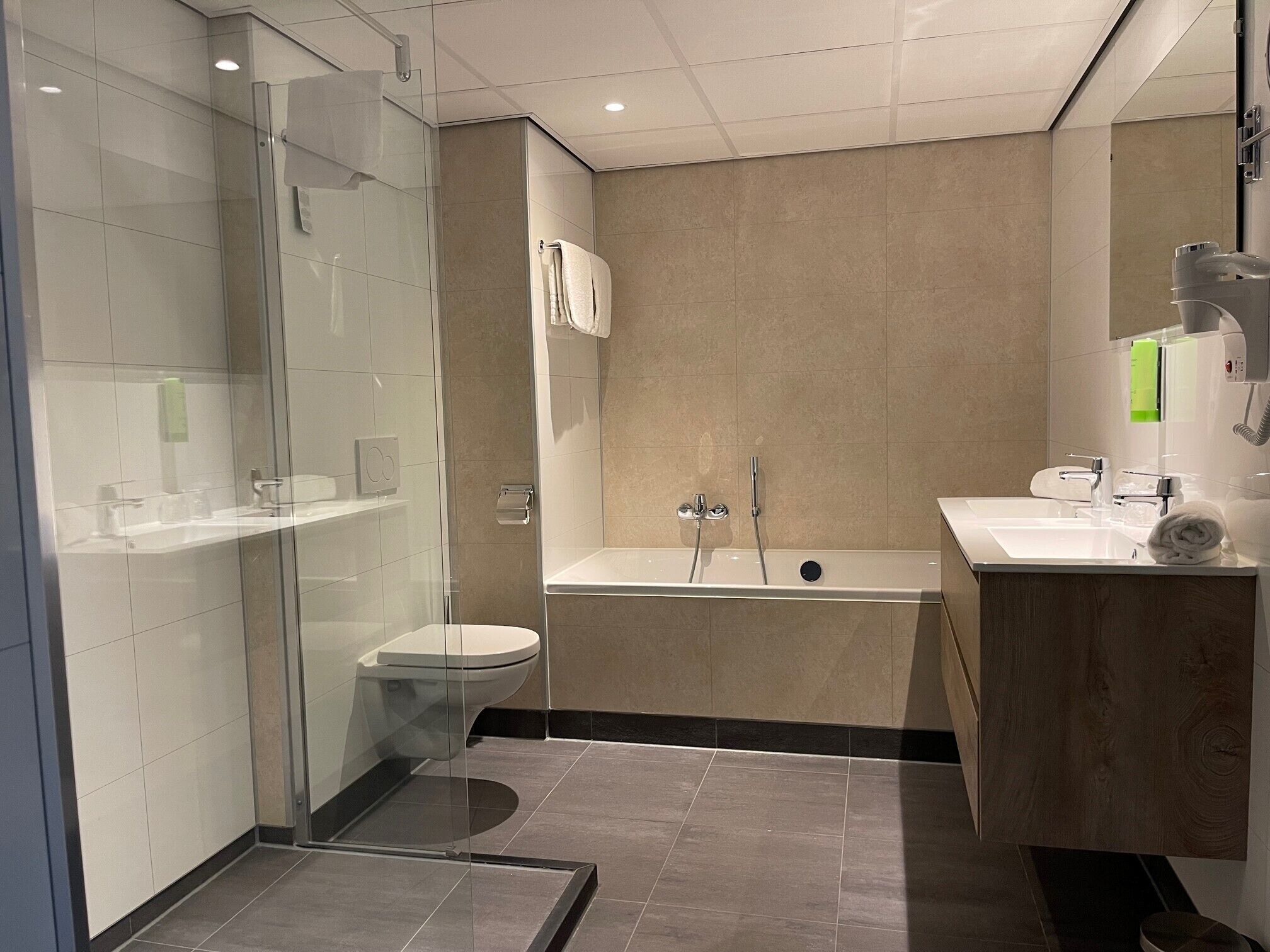 A modern bathroom with a glass-enclosed shower, a toilet, a bathtub, and a vanity with a mirror.