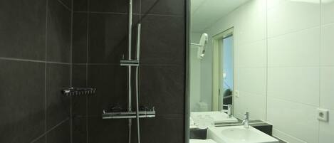 A modern bathroom with a dark tiled shower area, a glass-enclosed mirror, and a white sink with a countertop.