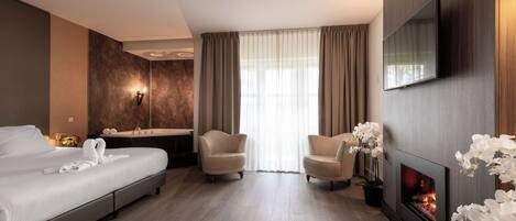 Una habitación de hotel con cama, sofá, sillón, chimenea y televisión.