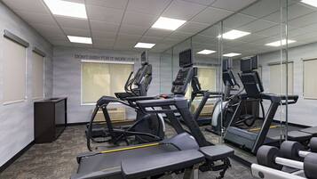 Une salle de sport équipée de tapis de course, d’un vélo d’appartement et d’appareils de musculation.