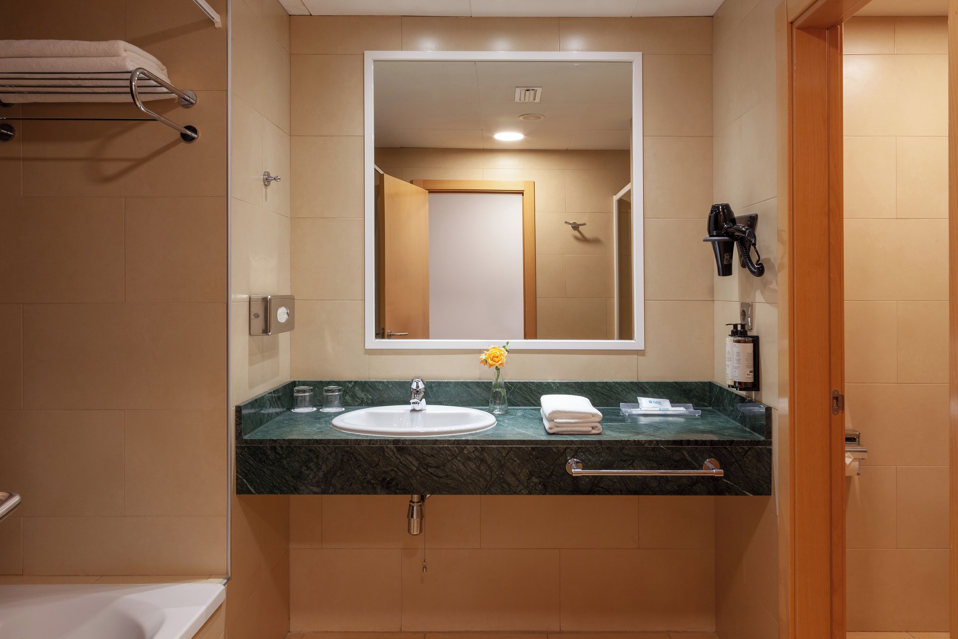 A bathroom with a sink, mirror, towel rack, and shower area.